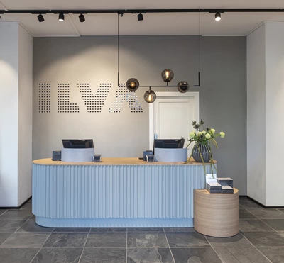 ILVAs eleganta butiksmiljö med en blå och träfärgad kassadisk, moderna pendellampor och en vägg med ILVA-logotypen