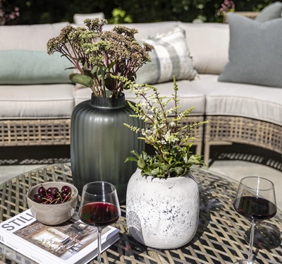 Loungeset och bord med vas och två glas rödvin