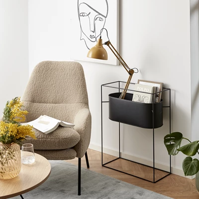 Fåtölj med gul lampa och svart tidningsställ