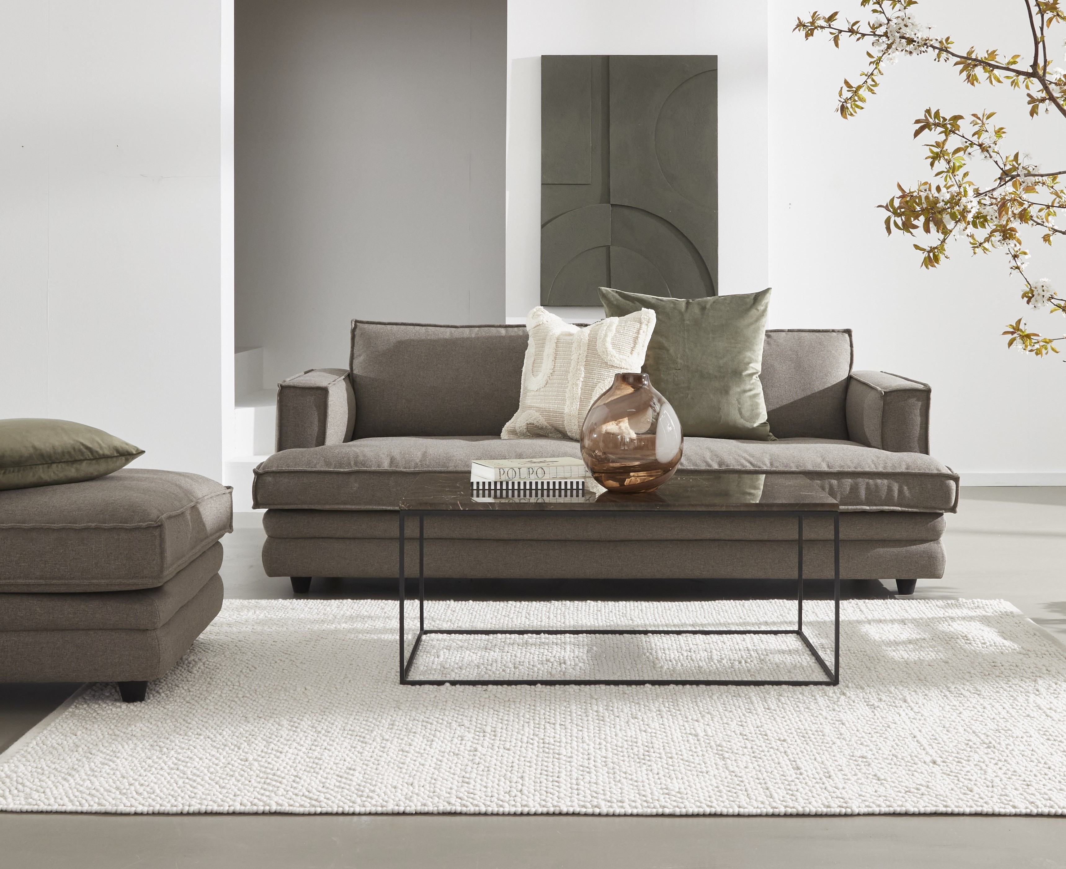 Stilfullt vardagsrum med brun soffa, glasbord och neutrala toner