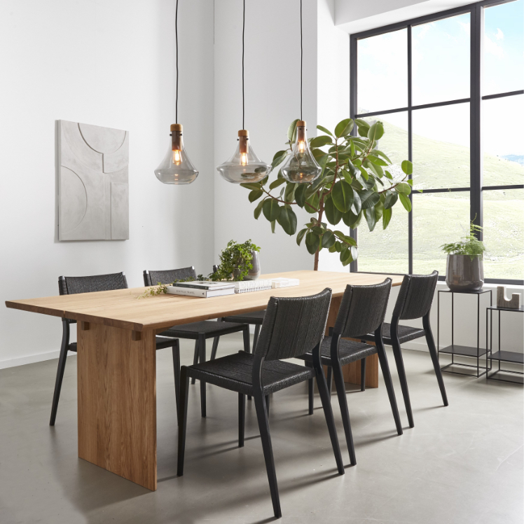 Modern matsal med träbord, svarta stolar och stora fönster