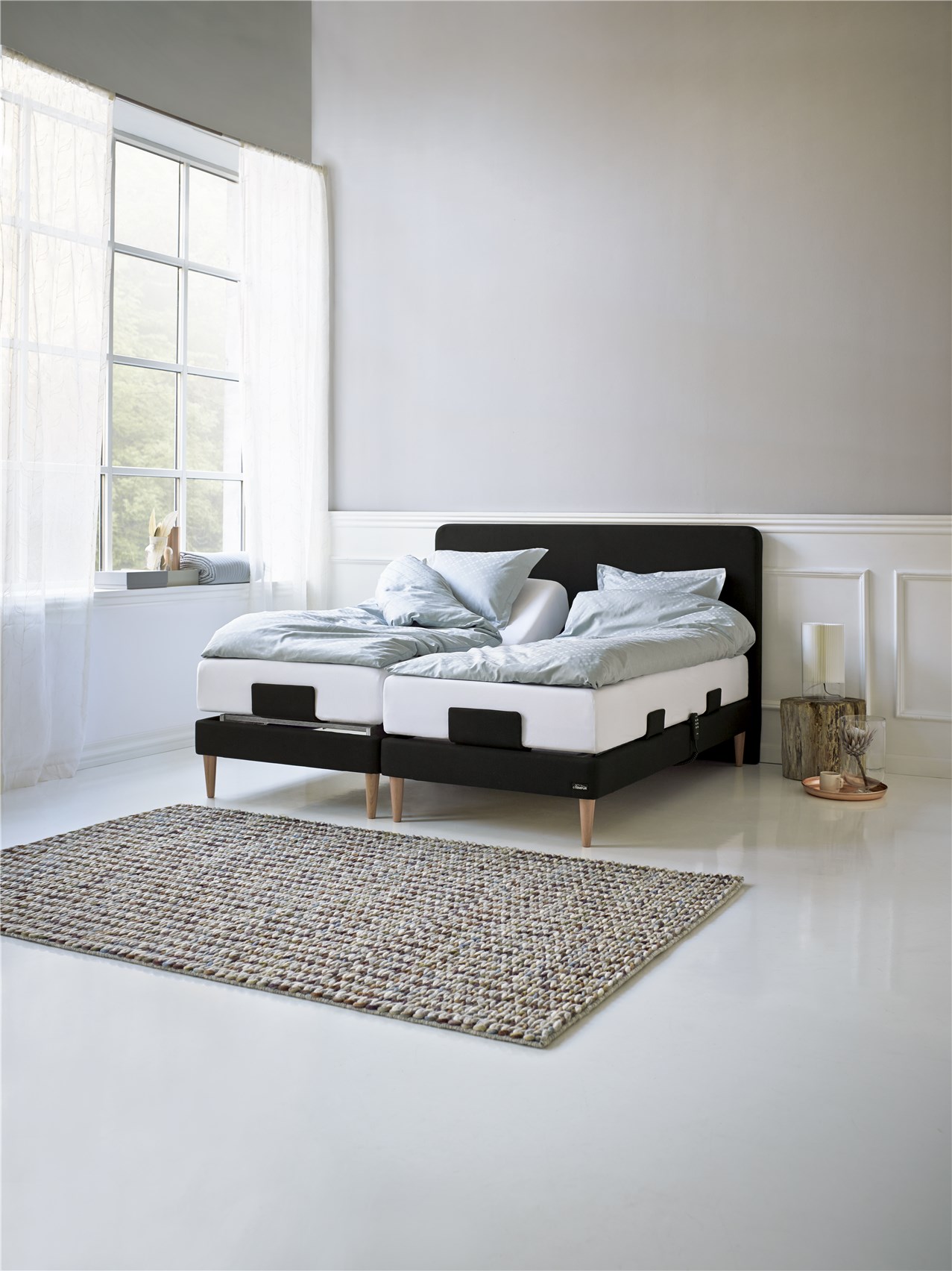 Ställbar säng med ljusblått bäddset och matta