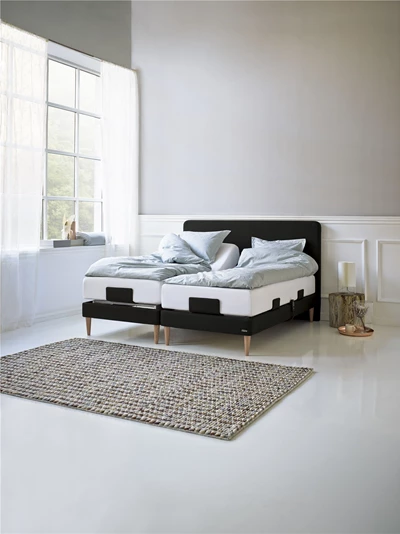 Ställbar säng med ljusblått bäddset och matta