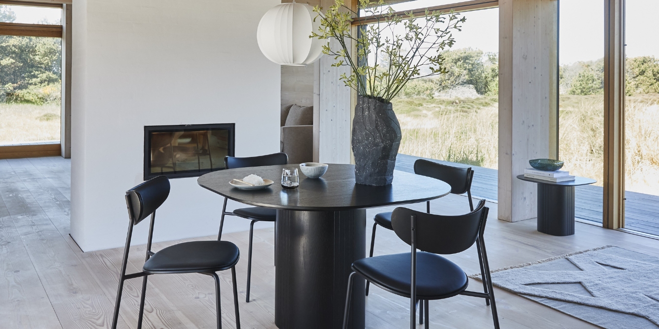 Svart runt matbord med fyra stolar och vas
