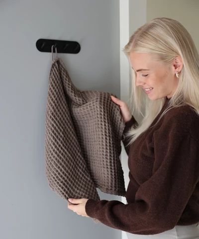 Kvinna hänger upp grått överkast på krok.