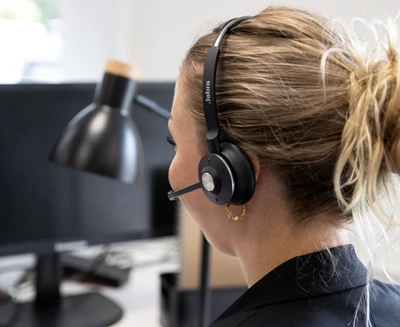 Kvinna med hörlurar som sitter framför datorn