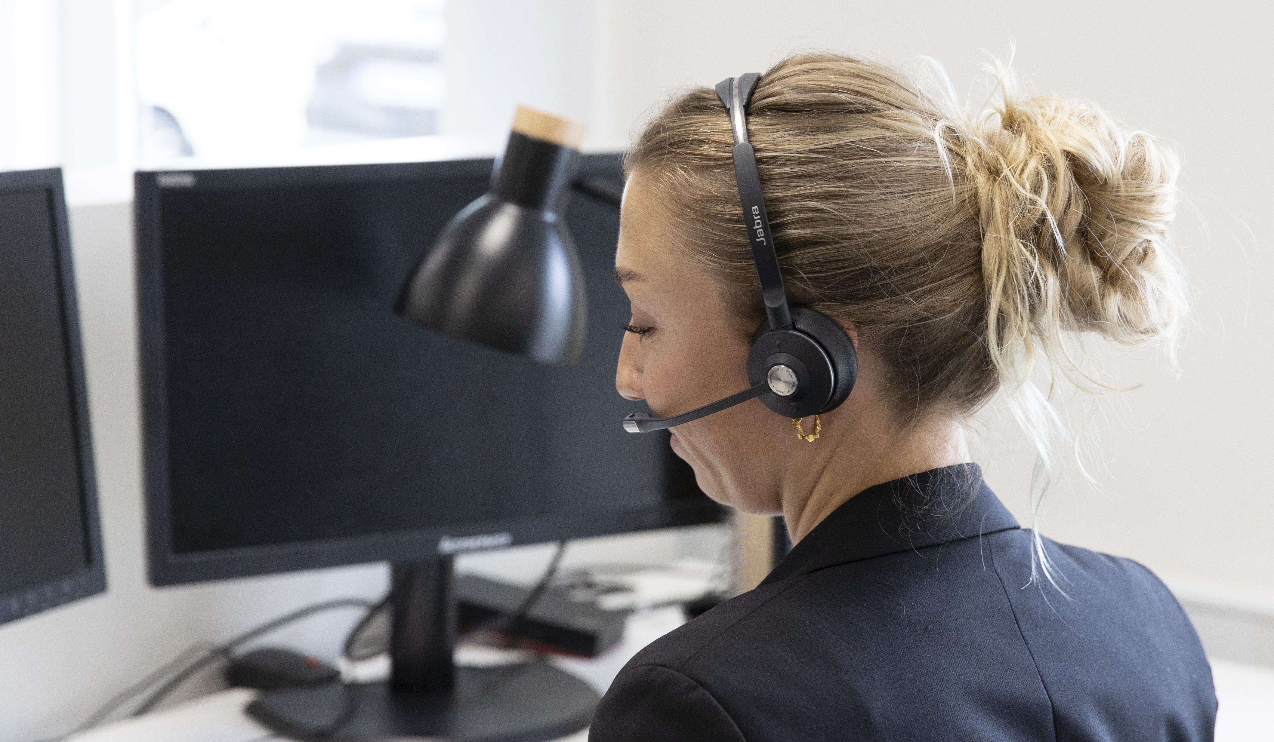 Kvinna med headset arbetar vid skrivbord med