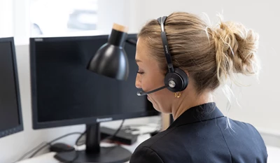 Kvinna med headset arbetar vid skrivbord med