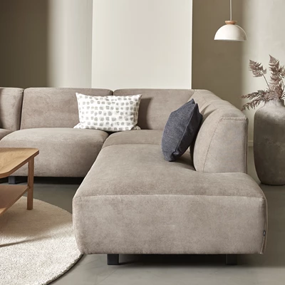 Hörnsoffa i beige med kuddar i olika mönster på.