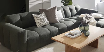 Grön soffa med rutigt utseende. Framför står ett soffbord i ljust trä.