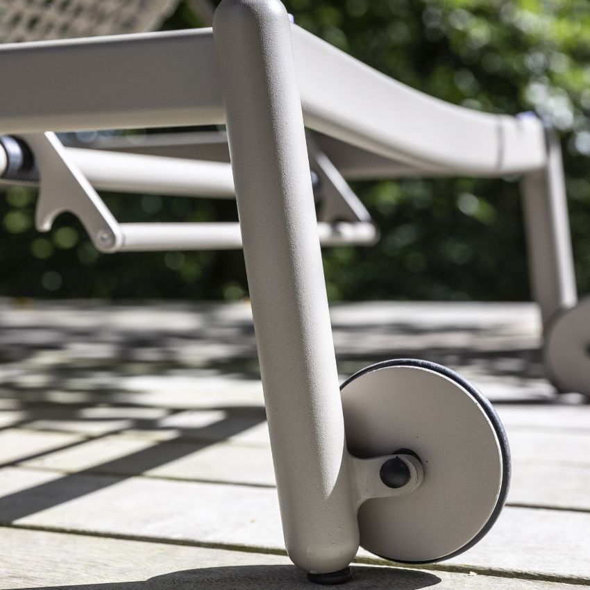 Närbild av ben och hjul på en modern solstol på en terrass med skuggiga mönster