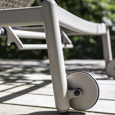 Närbild av ben och hjul på en modern solstol på en terrass med skuggiga mönster