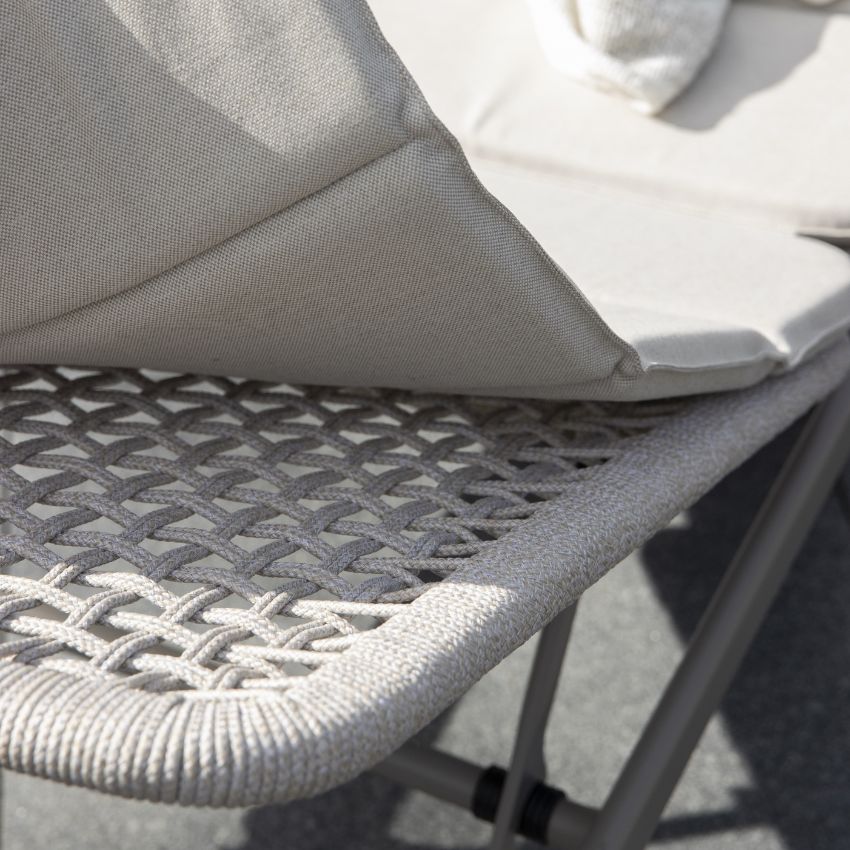 Detalj av det vävda mönstret på en solstols säte och en grå kudde.