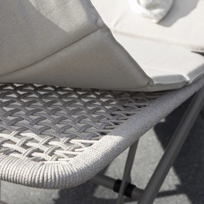 Detalj av det vävda mönstret på en solstols säte och en grå kudde.