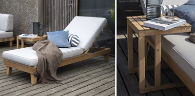 Träsolstol på en terrass med blå kudde och brunt täcke, bredvid kaffe och böcker.