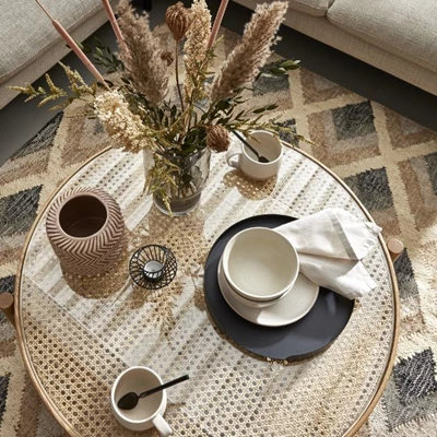 Diverse saker på soffbord, bland annat kaffekopp, vas och servett.