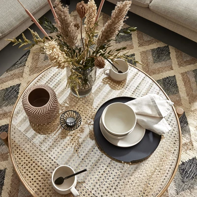 Diverse saker på soffbord, bland annat kaffekopp, vas och servett.