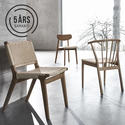 3 designstolar i trä stående utspridda på grått betonggolv