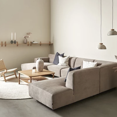 Vardagsrum med stor hörnsoffa, hylla och taklampor