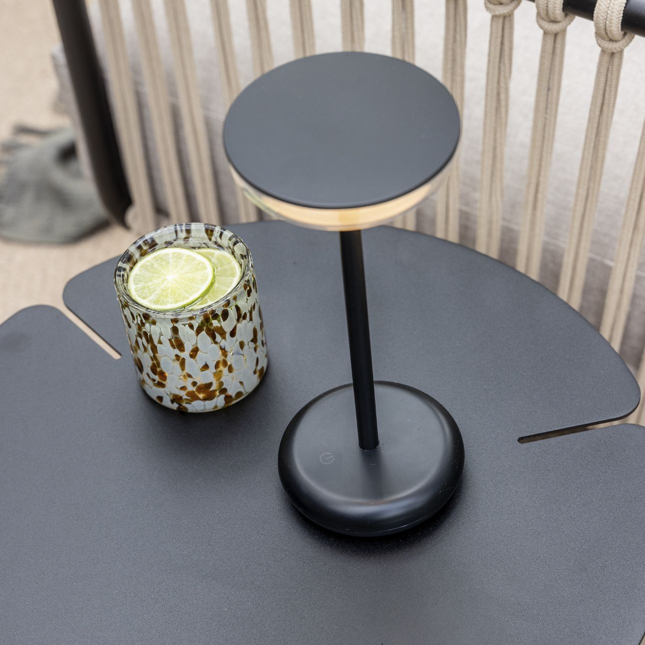 Bordslampa och drink på ett modernt svart bord på en terrass