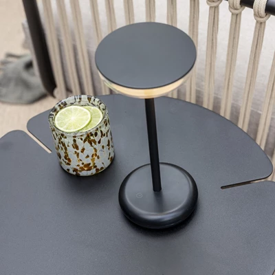 Bordslampa och drink på ett modernt svart bord på en terrass