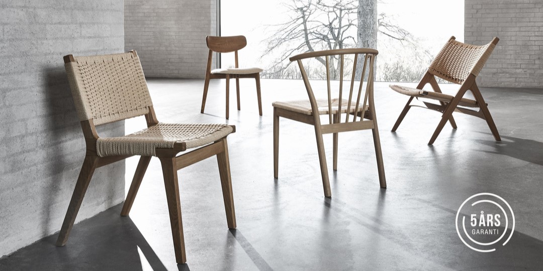 Fyra olika trästolar i ljust rum med garanti-logotyp