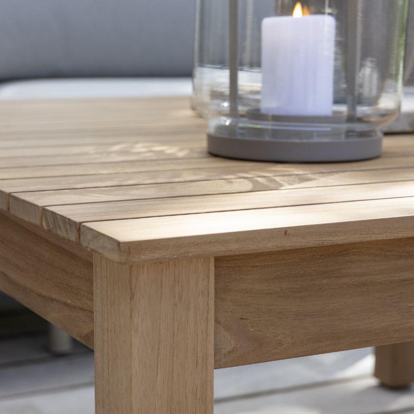 Närbild av ett träbord med en glaslykta med stearinljus på en överbyggd terrass