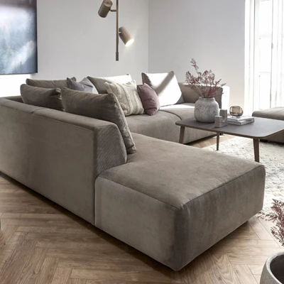 Modernt vardagsrum med en stor, brun hörnsoffa dekorerad med kuddar i neutrala färger, mörkt soffbord och dekorativa detaljer