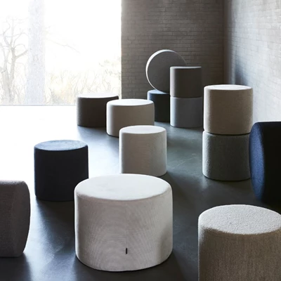 Samling av runda, stoppade puffar i neutrala färger, arrangerade i ett modernt rum med naturligt ljus