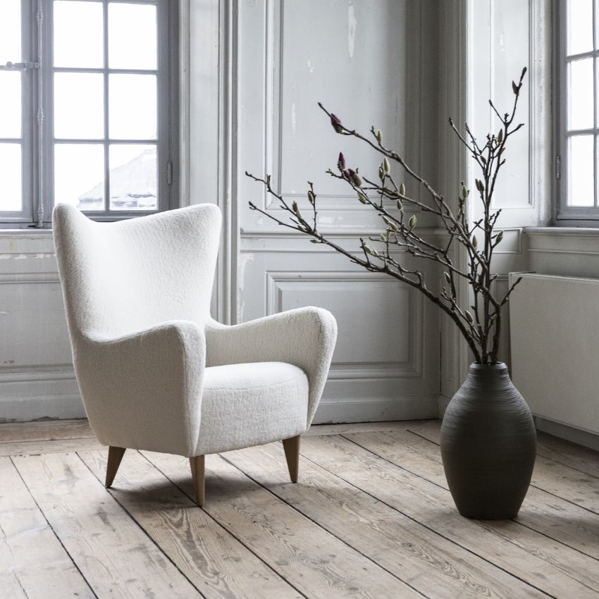 Elegant vit loungestol med träben i ett rum med klassiska fönster och en minimalistisk look.