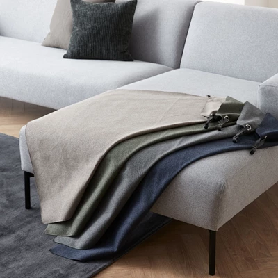 Ljusgrå soffa med dekorativa tygprover i blå, gröna och beige nyanser elegant draperade över schäslongen