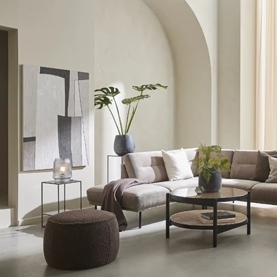 Lyxigt vardagsrum med en beige modulsoffa, runda soffbord och gröna växter, placerat i ett rum med välvda väggar och konst på väggen