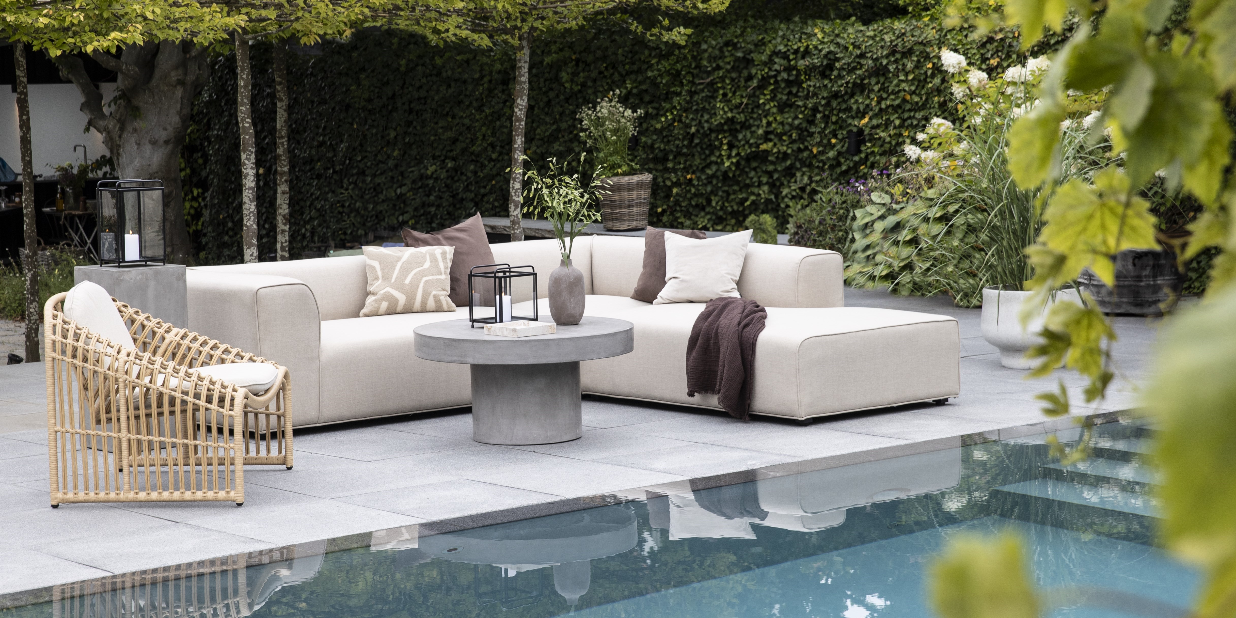 Loungesoffa och stol vid pool med grön bakgrund