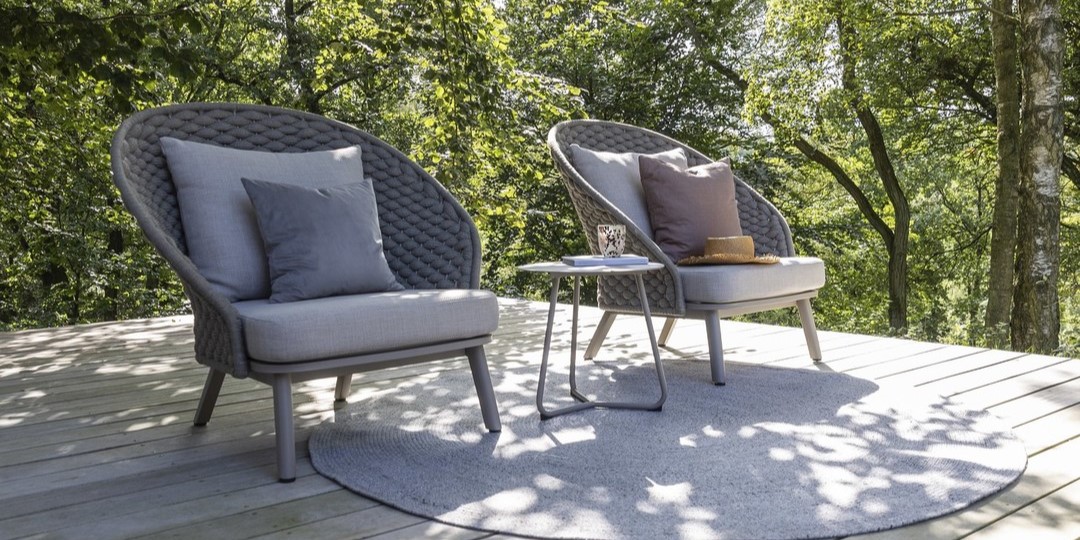 Två utomhus loungestolar med bord i skogsmiljö