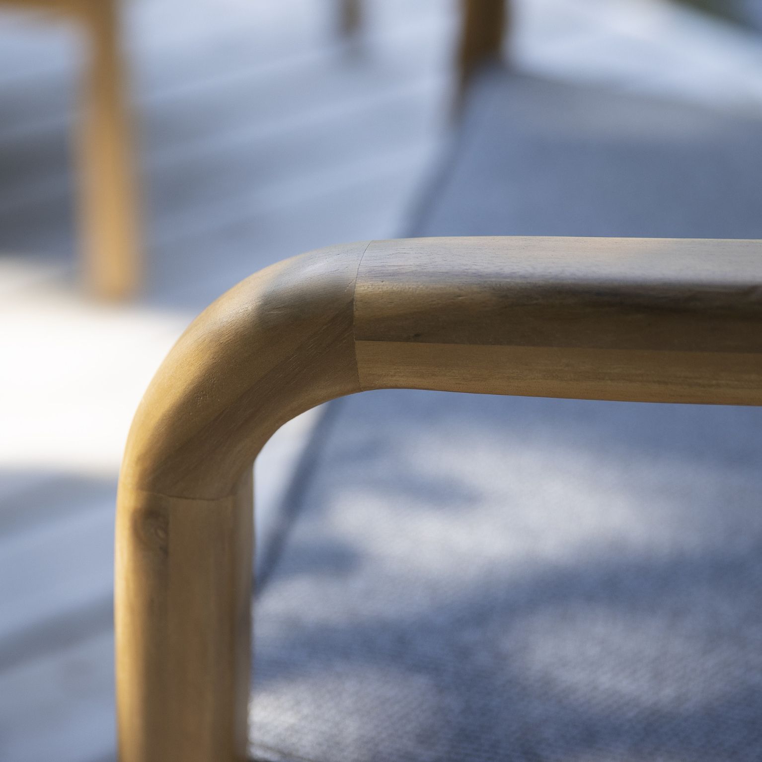 Detaljerad bild av armstödet på en trädgårdssoffa i akaciaträ