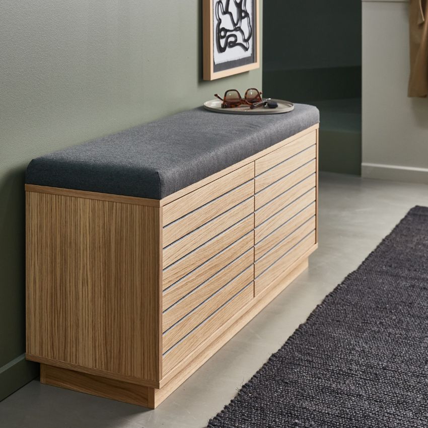 Låg träbänk med grå dyna och smart förvaring i hallmiljö.