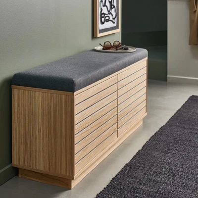 Låg träbänk med grå dyna och smart förvaring i hallmiljö.