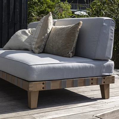 Låg loungesoffa i eukalyptusträ sedd snett från sidan.