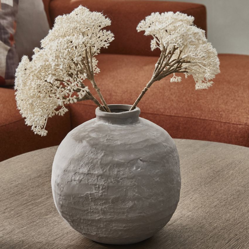 Grå och rund terrakottavas med vita blommor i.