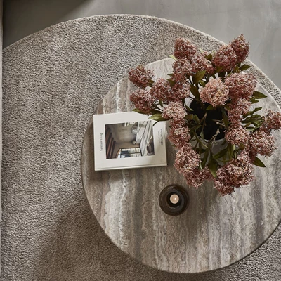 Soffbord sett uppifrån med en bok på samt en stor bukett blommor och en liten ljusstake