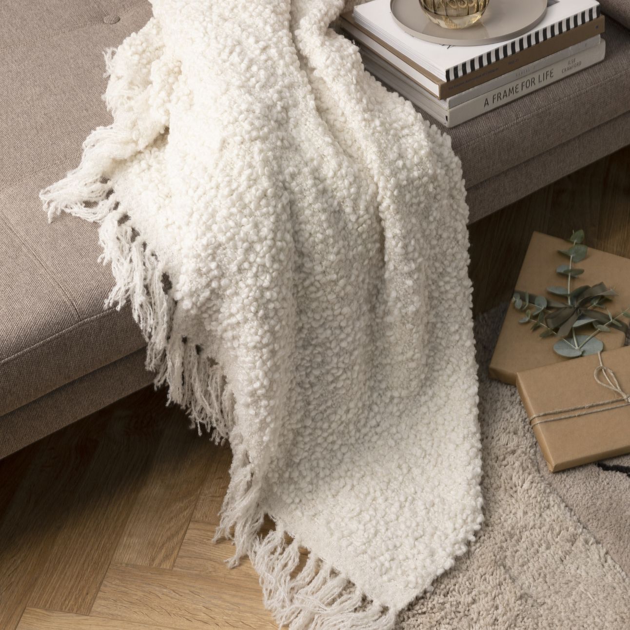 Vitt pläd slängd på soffa i vardagsrum