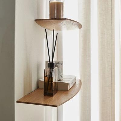 Vägghylla i trä med olika prydnadssaker placerade på