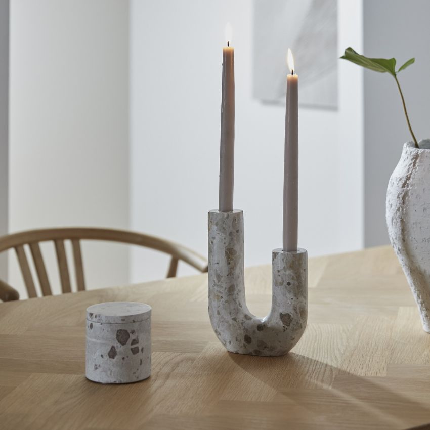 Förvaringsburk och ljusstake i brunaktig marmor stående på ett trämatbord