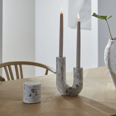 Förvaringsburk och ljusstake i brunaktig marmor stående på ett trämatbord