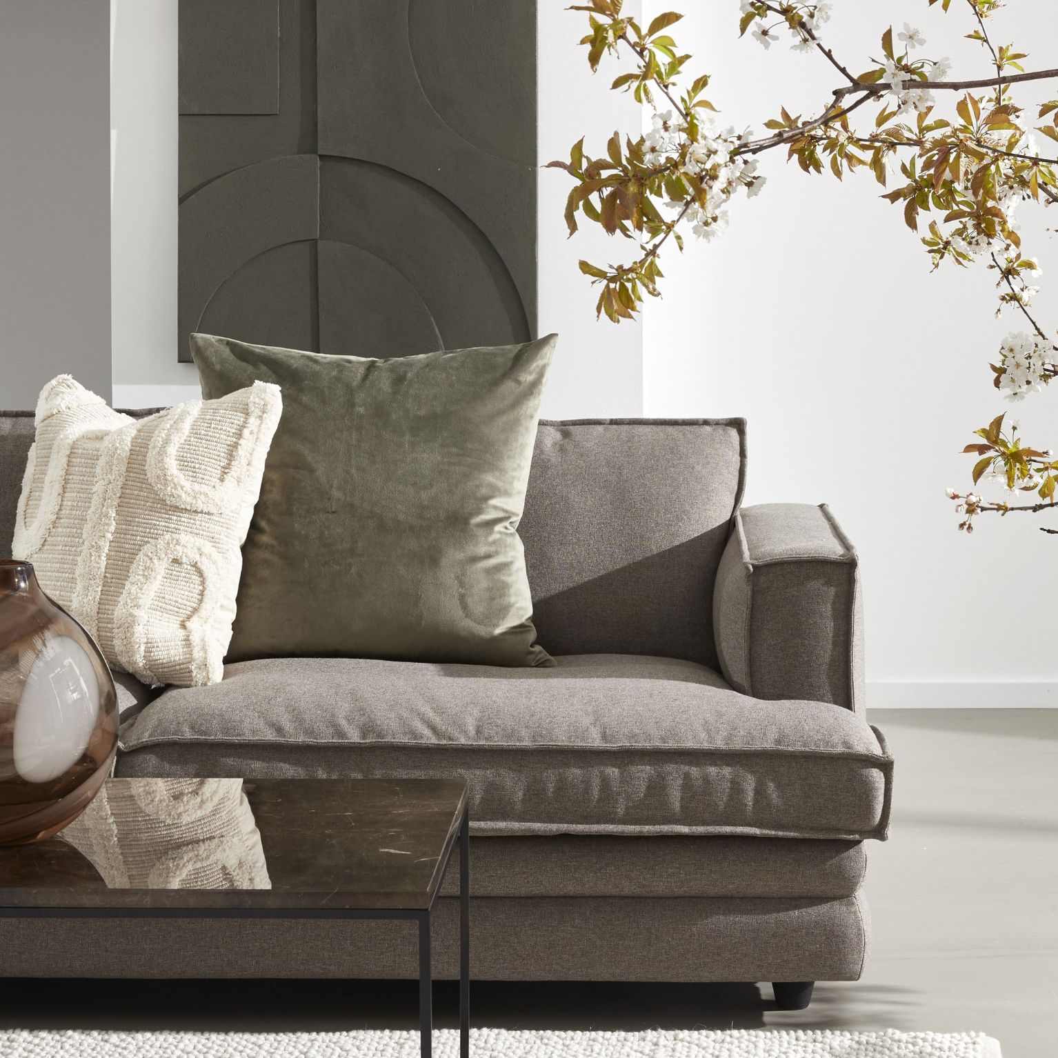 Halva soffan i Soil-tyg stående vid soffbord i svart metall och vit matta