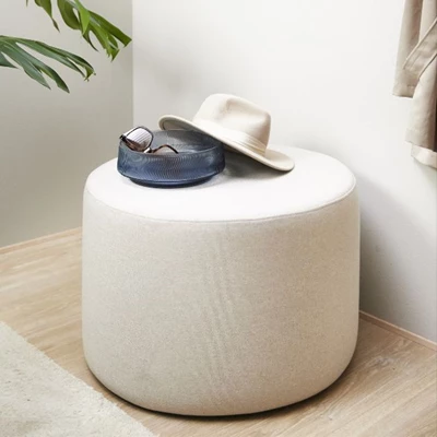 Vit puff med en vas stående ovanpå, innehållande solglasögon samt en hatt