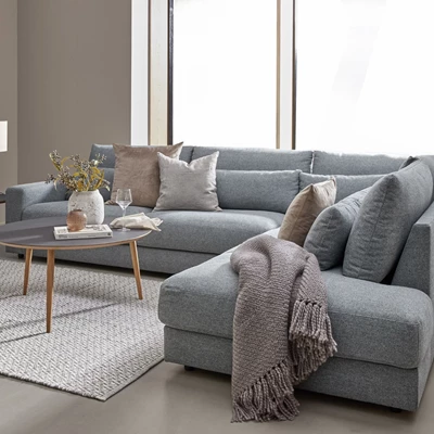 Soffarrangemang i gråa nyanser med kuddar, pläd, matta, soffbord, m.m.