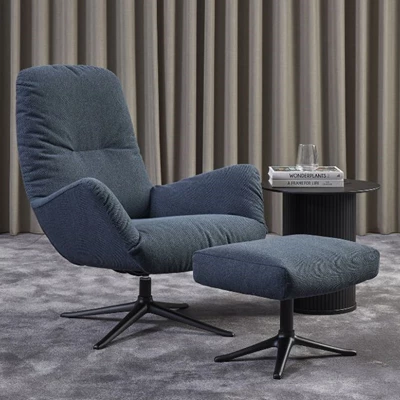 Fåtölj med fotpall, båda med svarta ben, i Denno-tyg från ILVA tyg- och läderkollektion  Puff i grått tyg och med svarta metallben stående på trägolv framför altandörr