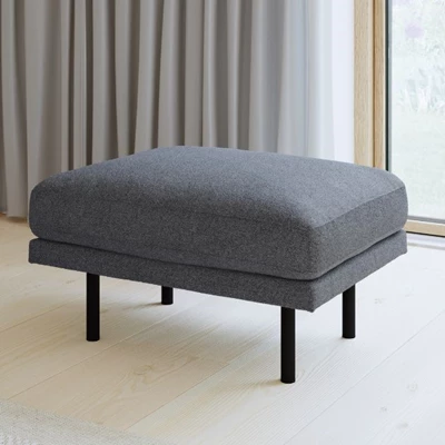 Puff i grått tyg och med svarta metallben stående på trägolv framför altandörr