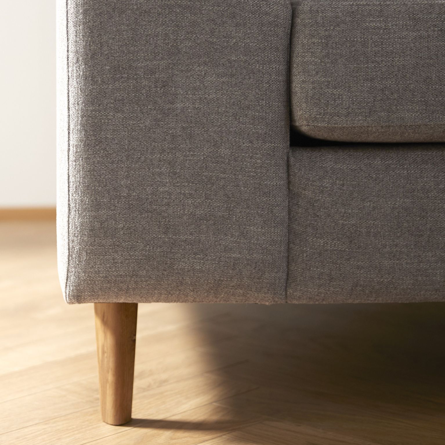 Närbild av soffa i grått med träben